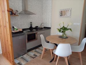 a kitchen with a wooden table and white chairs at Casa Da Ponte in Lobios +3 photos