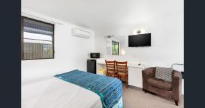 a room with a bed and a desk and a chair at A&A Lodge Motel in Emerald