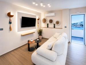 a living room with a white couch and a tv at Vista Maris Suites in Amoopi
