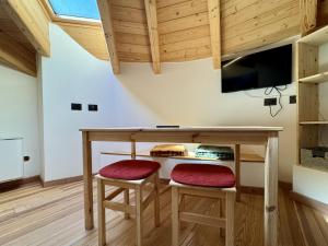 a room with a table with two stools and a tv at Freeabile 51 - Cevedale - stanza in centro in Sondrio