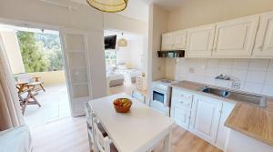 a kitchen with white cabinets and a table with a bowl of fruit on it at Andrikos Studios in Lákka