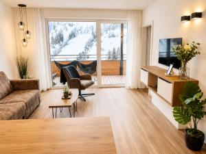 a living room with a couch and a television at Alpenstolz Damüls Haus 2 - Stilvoll urlauben in den Bergen in Damuls
