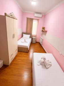two beds in a room with pink walls and wooden floors at Dreamers Hostel & Hotel Apartment in Yerevan
