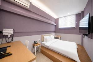 a bedroom with a bed and a desk and a tv at NU Hotel in Cheonan