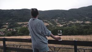 Ein Mann steht auf einem Zaun und hält ein Glas Wein. in der Unterkunft krupajsko vrelo in Milanovac