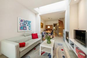 a living room with a white couch and a tv at Parkhuisje by BLOSS in Bruges
