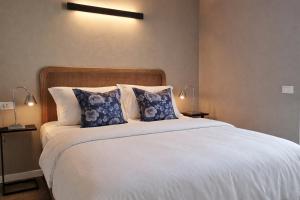 a bedroom with a large white bed with blue pillows at Lake Como Terrace Suite in Mandello del Lario