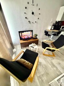a living room with two chairs and a clock on the wall at Petit Nid Nature Et Douceurs in Turckheim