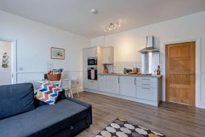 a living room with a blue couch and a kitchen at Dizzy Lows Modern 1 Bedroom Swanage Apartment with Sea View in Swanage