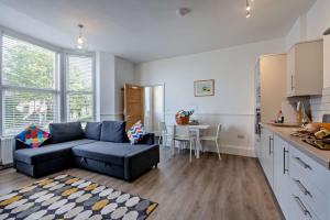 a living room with a blue couch and a kitchen at Dizzy Lows Modern 1 Bedroom Swanage Apartment with Sea View in Swanage