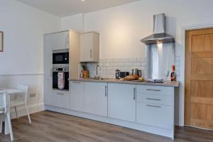 a kitchen with white cabinets and a stove top oven at Dizzy Lows Modern 1 Bedroom Swanage Apartment with Sea View in Swanage