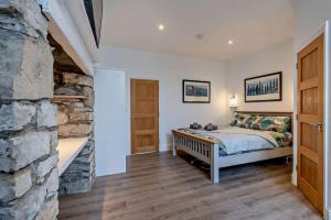 a bedroom with a bed and a stone wall at Dizzy Lows Modern 1 Bedroom Swanage Apartment with Sea View in Swanage +11 photos