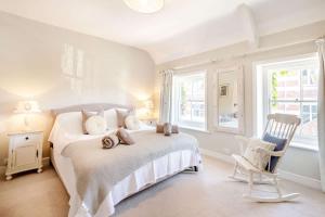 a white bedroom with a bed and a chair at Passiflora Cottage Close to Swanage Beach and Town Sleeps 7 in Swanage