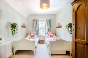 two beds in a room with a window at Passiflora Cottage Close to Swanage Beach and Town Sleeps 7 in Swanage