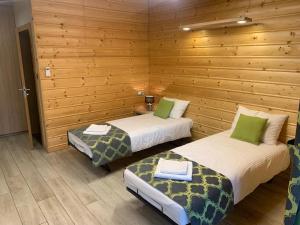two beds in a room with wooden walls at Pod Grzybkiem in Zawady