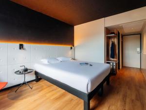 a bedroom with a large white bed and a table at ibis Styles Lyon Sud Vienne in Chasse-sur-Rhône +73 photos