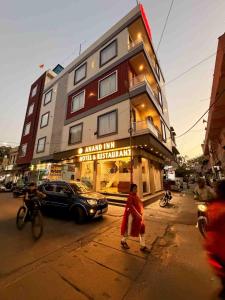 a woman walking down a street in front of a building at Hotel Anand Inn in Kota