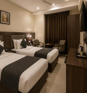ein Hotelzimmer mit zwei Betten und einem Schreibtisch in der Unterkunft Hotel Smart Snap Sector 104, Noida in Noida