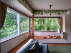 a living room with a couch and two large windows at みどりの風 -那須高原中心地-森を感じる貸切一軒家-観光や買い物に便利-無料bbq-最大7名-子供歓迎 in Nasu +7 photos