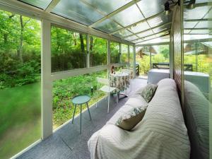 a glass house with a couch in a screened in porch at みどりの風 -那須高原中心地-森を感じる貸切一軒家-観光や買い物に便利-無料bbq-最大7名-子供歓迎 in Nasu