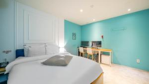 a bedroom with a large white bed and a desk at NU Hotel in Cheonan
