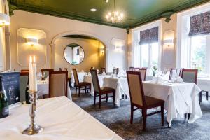 a restaurant with white tables and chairs and a mirror at Bagden Hall Hotel in Scissett