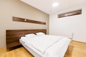 a bedroom with a white bed with a wooden headboard at Anenské terasy in Brno