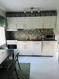 a white kitchen with white cabinets and a table at Small Cozy apartment with Wi-Fi in Tjørhom