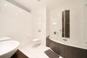 a white bathroom with a toilet and a tub and a sink at Anenské terasy in Brno +18 photos