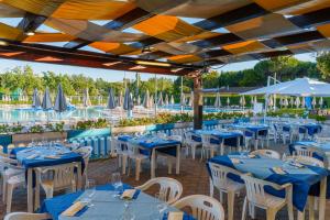 a restaurant with blue tables and white chairs and umbrellas at Club del Sole Le Gorette Cecina Easy Camping Village in Marina di Cecina
