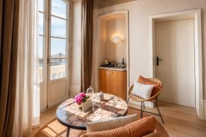 a living room with a table and chairs and a window at ROSEMARY hôtel in Bastia