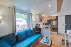 a living room with a blue couch and a kitchen at Siblu Duinzicht in Koudekerke