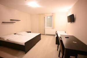 a bedroom with a bed and a desk and a television at Fürdőkerti Ifjúsági Szálló in Hajdúböszörmény
