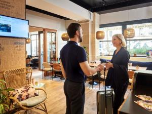 a man and a woman with a suitcase in a restaurant at Ibis Styles Hotel Paris Gare de Lyon Bastille in Paris
