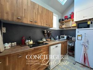 a kitchen with wooden cabinets and a white refrigerator at Le Nid du Matelot in Saint-Vaast-la-Hougue +3 photos