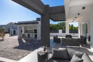 a patio of a house with a couch and tables at Villa della Rode in Lozovac