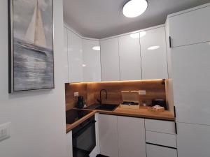 a kitchen with white cabinets and a counter top at Luxury Mint Garden Apartment in Kaštela