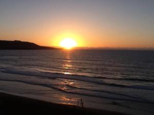 a sunset on the beach with the ocean at Numancia 1 - 2A in Las Palmas de Gran Canaria