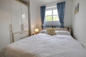 a bedroom with a large white bed with a window at Syltglück in Westerland