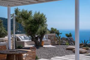 a patio with a tree and a couch and a table at NeRó Villas Lefkada in Tsoukalades