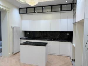 a kitchen with white cabinets and a black counter top at Casa de prime in Baku