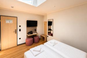 a white bedroom with a bed and a television at Nivara Hotel in Hamburg