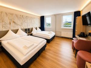 a hotel room with two beds and a television at Nivara Hotel in Hamburg
