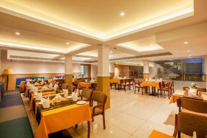 a restaurant with yellow tables and chairs and tables and chairs at HOTEL GANGa in Mūvattupula