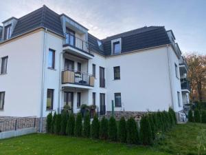 a white house with a black roof at OMNI - Homes - Waldstraße in Falkensee