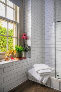 a white tiled bathroom with a bench and a window at Crown & Punchbowl in Cambridge +28 photos
