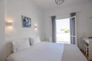 a white bedroom with a bed and a window at Avra Pension in Ios Chora