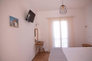 a bedroom with a bed and a tv on a wall at Avra Pension in Ios Chora