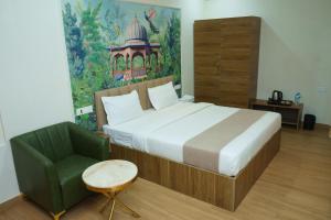 a bedroom with a large bed and a green chair at Sweekar Executive in Tuljapur