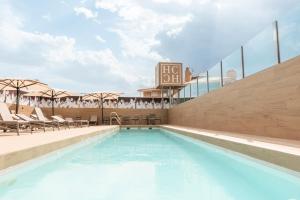 a swimming pool with chairs and a hotel sign at Hotel Andalucía Center in Granada